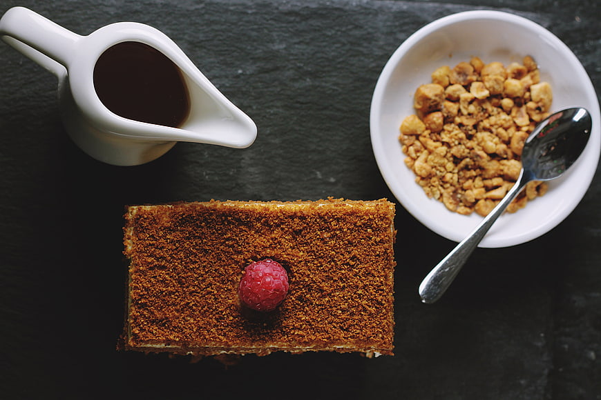 Flat lay of layered cake, coffee, and granola on dark slate