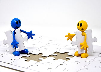 Blue and yellow figurines holding puzzle pieces on white background