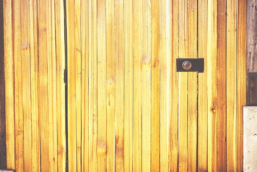 Close-up of yellow wooden fence with black keyhole