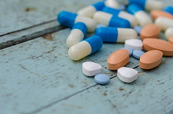 Assorted Pills and Capsules on Rustic Blue Wooden Surface
