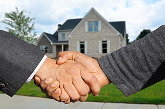 Business handshake in front of suburban house for real estate