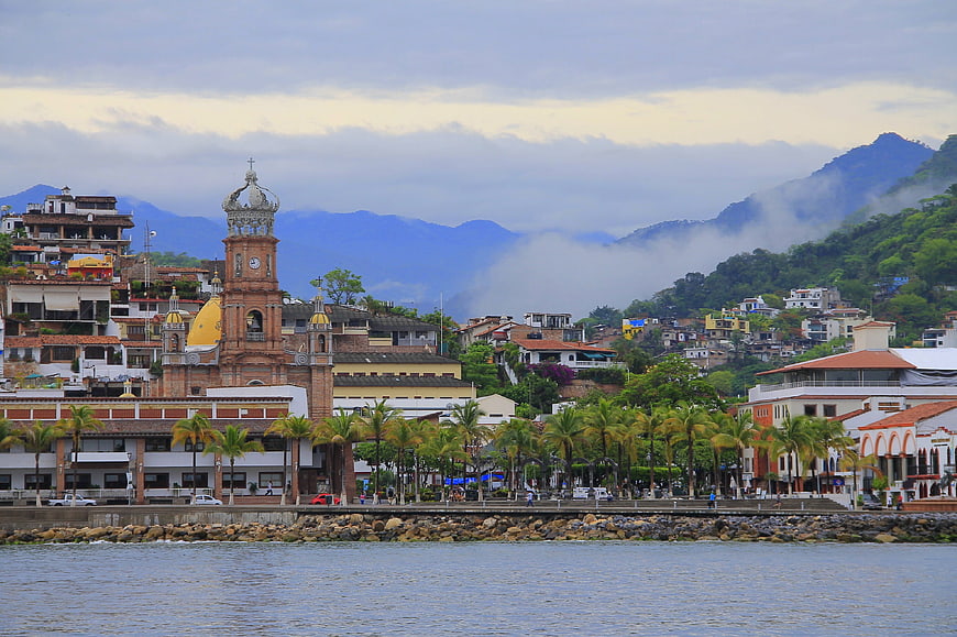 Coastal town with church, palm trees, and mountains