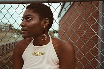 Stylish Black Woman with Pink Eyeliner by Chain Link Fence