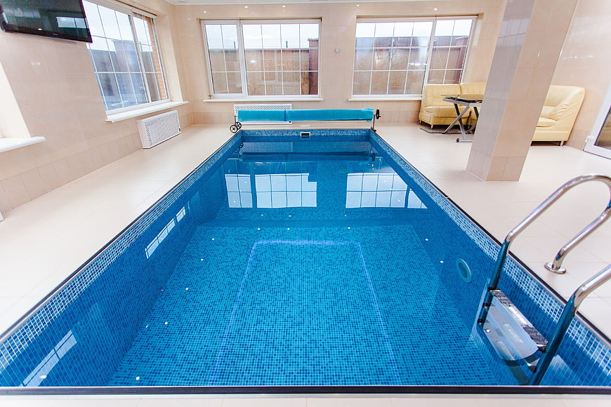 Indoor Swimming Pool with Blue Tiles and Relaxation Area