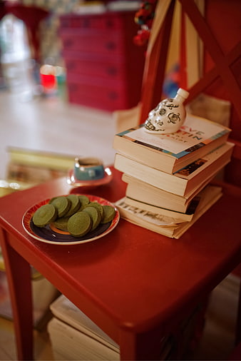 Stack of books and green cookies on red table