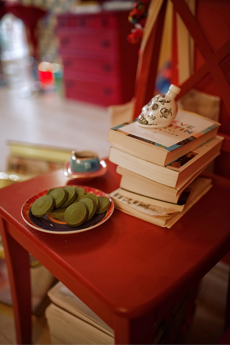 Stack of books and green cookies on red table