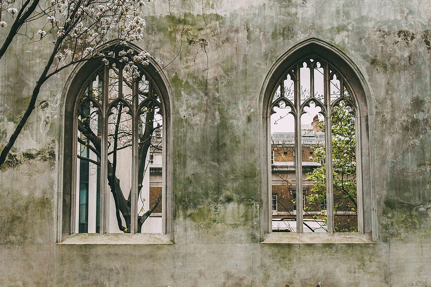 Gothic arched windows on weathered stone wall with spring blossoms