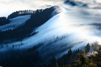 Dramatic Fog Wave Flowing Over Snowy Winter Mountain Landscape