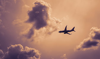 Airplane Silhouette Flying Through Dramatic Sunset Clouds