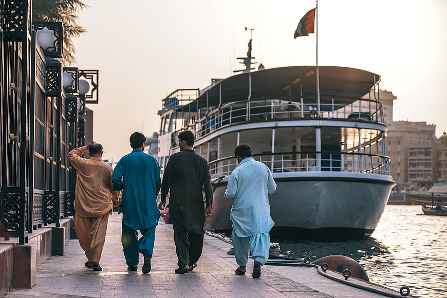Men in Traditional Thobes Walking Along Dubai Creek Waterfront