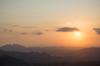 Golden sunset over layered mountain ranges with clouds