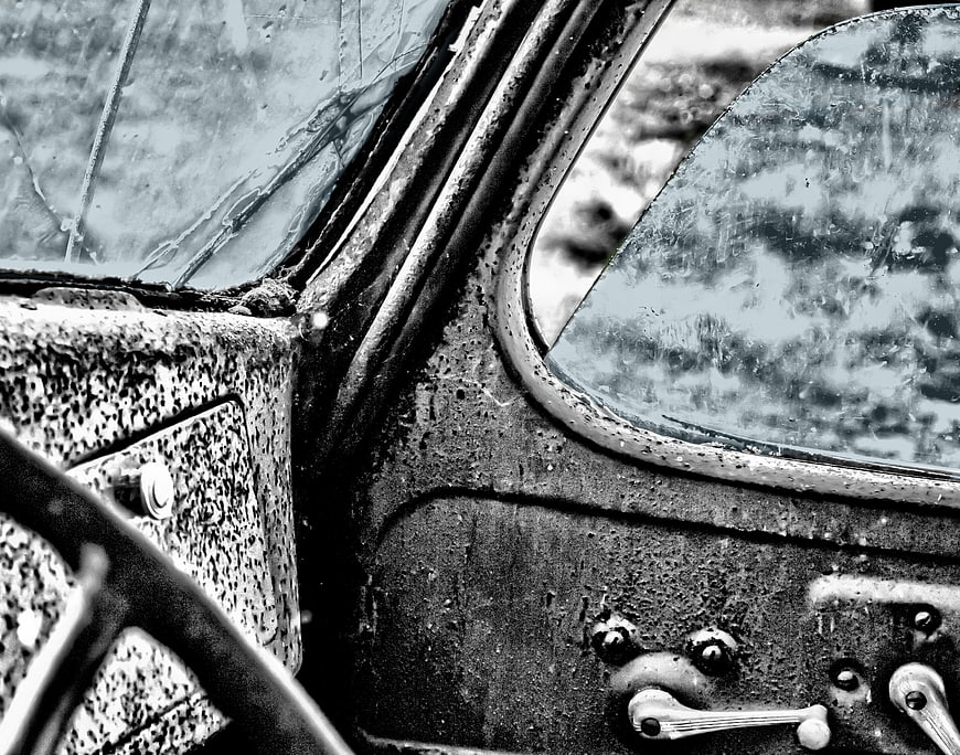 Close-up of weathered vintage car cockpit interior in black and white