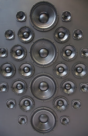 Symmetrical arrangement of various speaker drivers on a gray wall