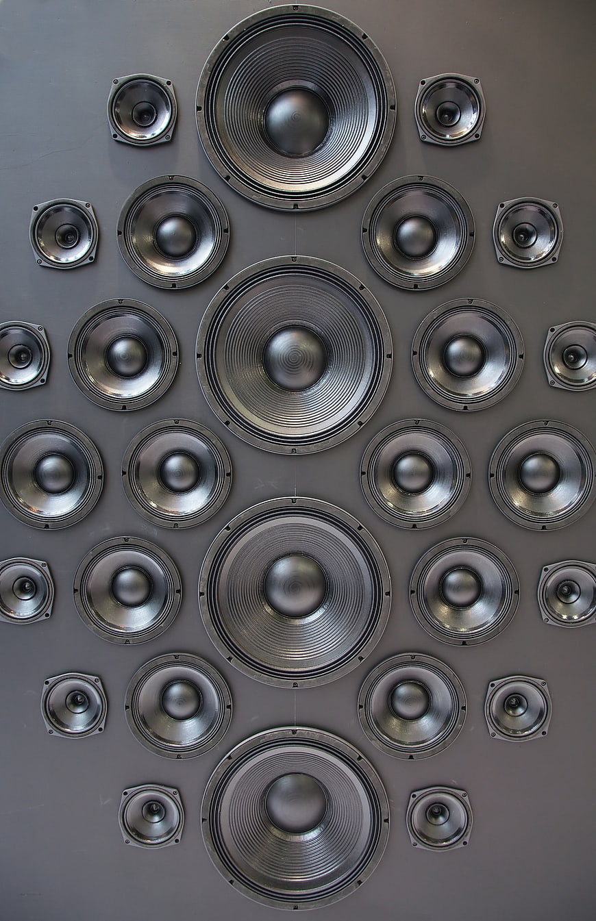 Symmetrical arrangement of various speaker drivers on a gray wall