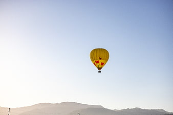 Yellow Hot Air Balloon Flying Over Hazy Mountains