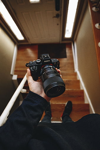 First-person view holding Sony camera on wooden stairs