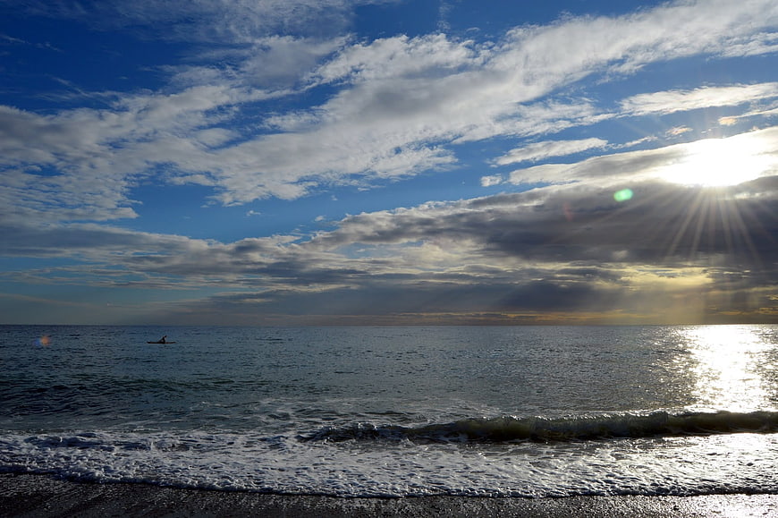 Sunset over ocean with kayaker and dramatic clouds