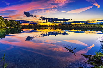 Vibrant sunset reflection on calm lake with colorful clouds