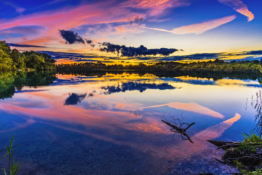 Vibrant sunset reflection on calm lake with colorful clouds