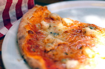 Close-up of cheesy pizza slice on white plate