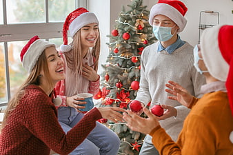 Friends celebrating Christmas with masks and Santa hats