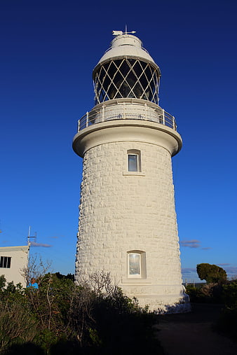White stone lighthouse against deep blue sky
