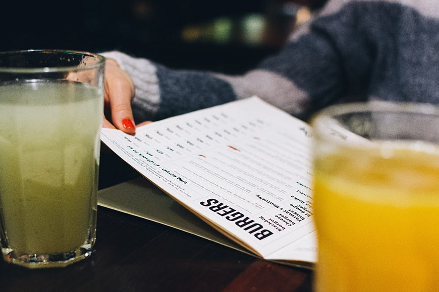 Close-up of hands holding a burger menu with drinks