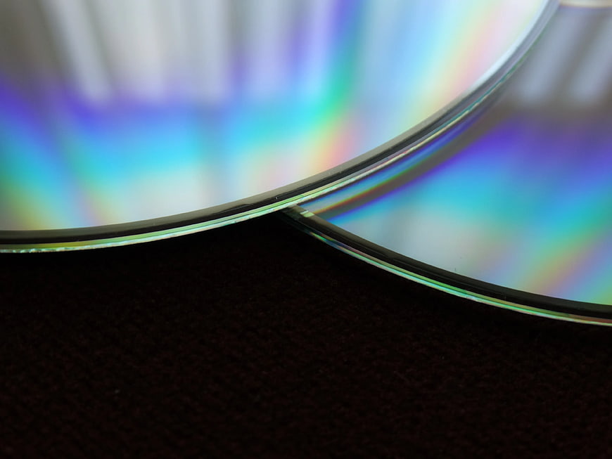 Close-up of iridescent optical disc edge on dark background