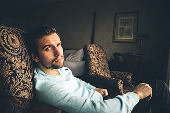 Portrait of a young man sitting in a vintage armchair