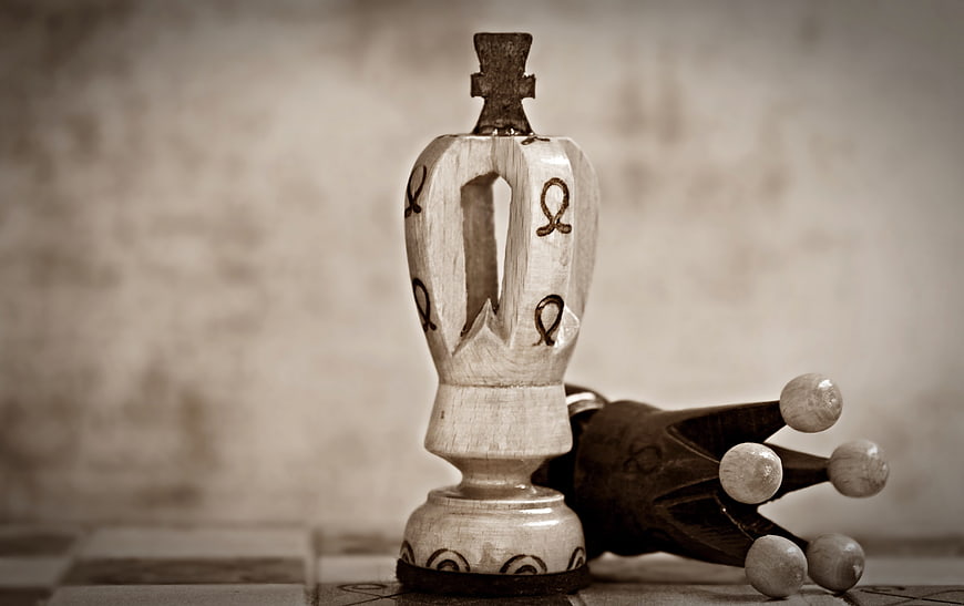 Vintage wooden chess queen and fallen king on a checkered board