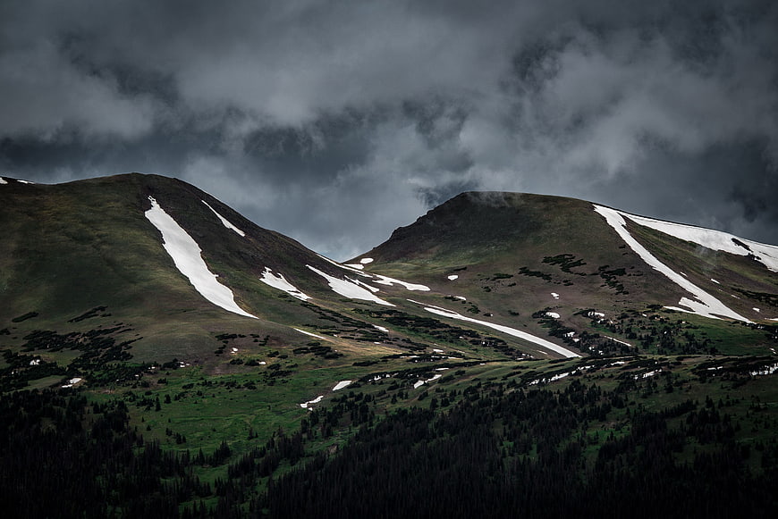 Dramatic Mountain Peaks with Snow Patches Under Stormy Clouds