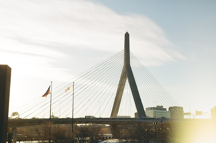 Modern cable-stayed bridge with American flag and sun flare