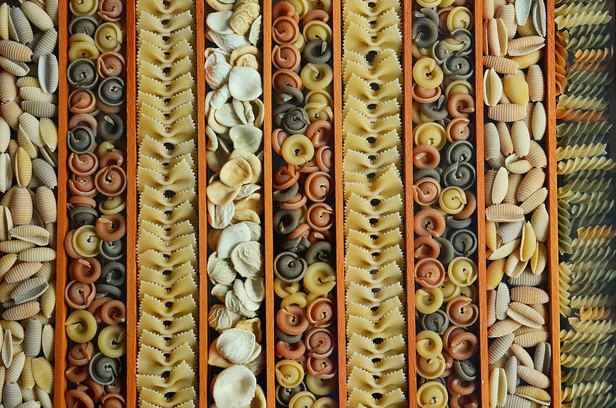 Top View of Sorted Colorful Pasta Shapes in Wooden Compartments