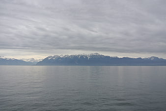 Serene Lake View with Snow-Capped Mountains Under Cloudy Sky