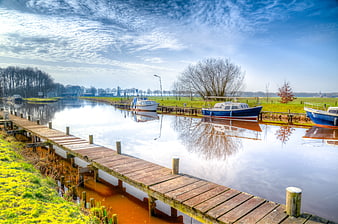 Wooden pier and boats in Dutch canal landscape