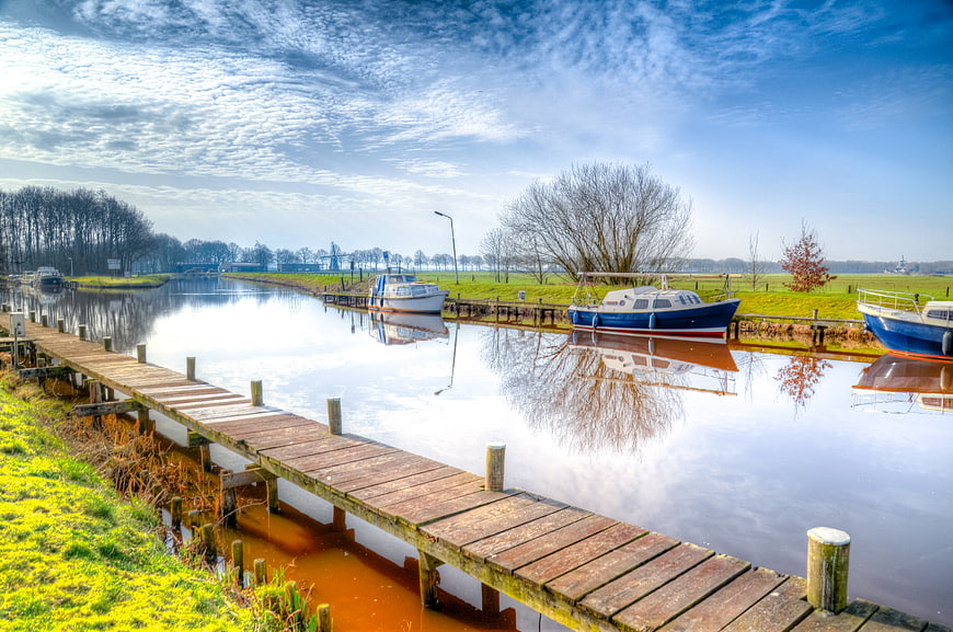 Wooden pier and boats in Dutch canal landscape