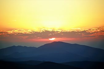 Golden Sunrise Over Layered Mountain Silhouettes