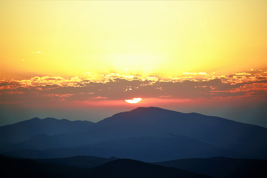 Golden Sunrise Over Layered Mountain Silhouettes