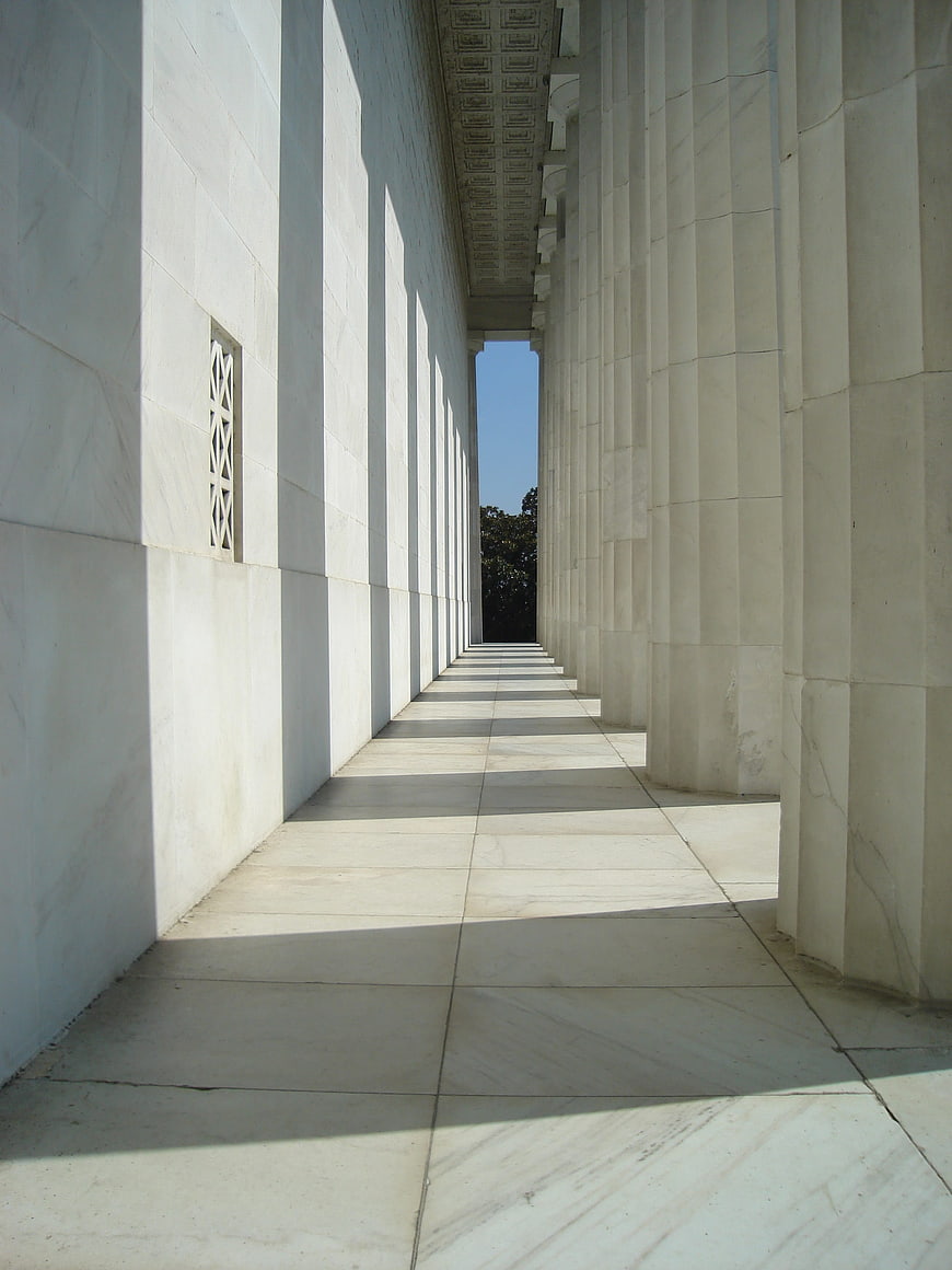 Perspective view of white marble columns and shadows in a classical arcade