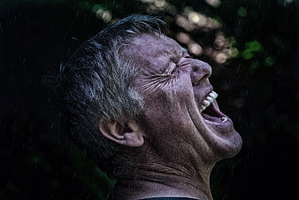 Dramatic Close-Up Portrait Of Elderly Man Laughing In The Rain