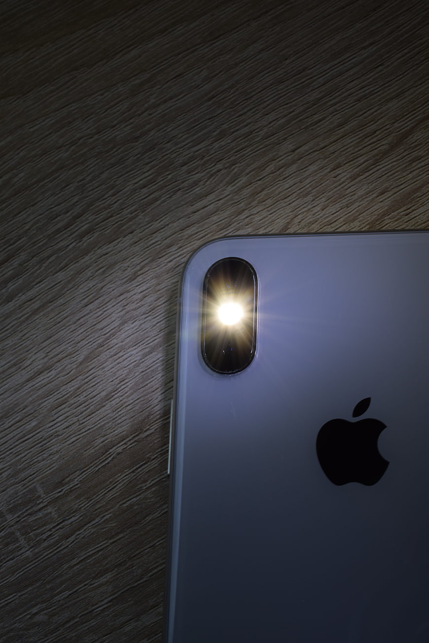 Close-up of iPhone X rear camera and flash on wooden surface