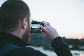 Man Taking Photo of Sunset with Smartphone