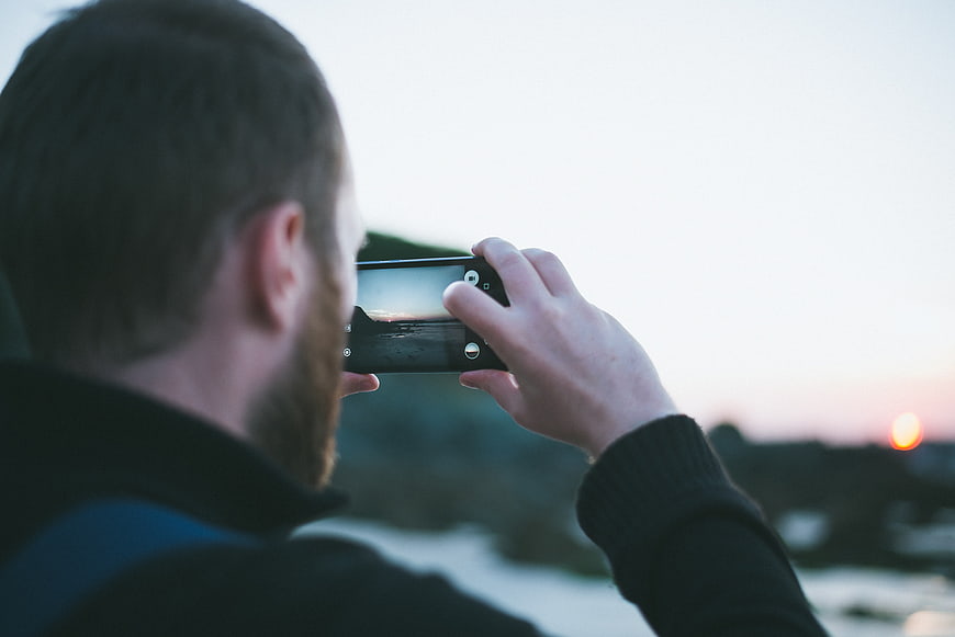 Man Taking Photo of Sunset with Smartphone