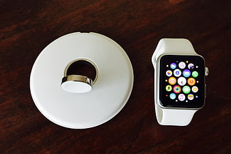 White Smartwatch and Wireless Charger on Dark Wood