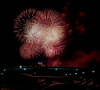Red and white fireworks exploding over Olympic stadium at night