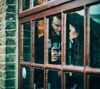 Couple looking at smartphone through cafe window