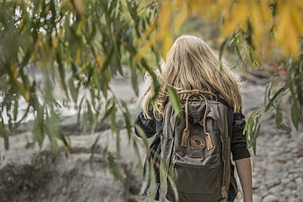 Girl with Backpack Walking Through Autumn Trees