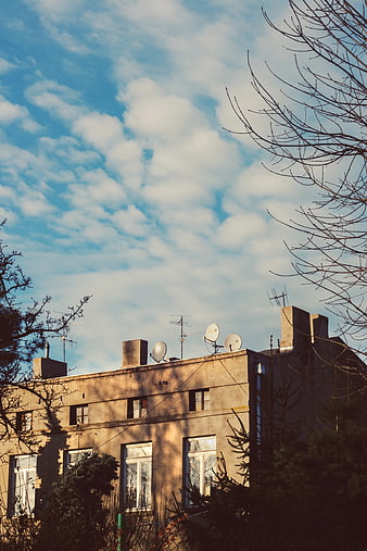 Old Tenement Building with Satellite Dishes Against Blue Sky