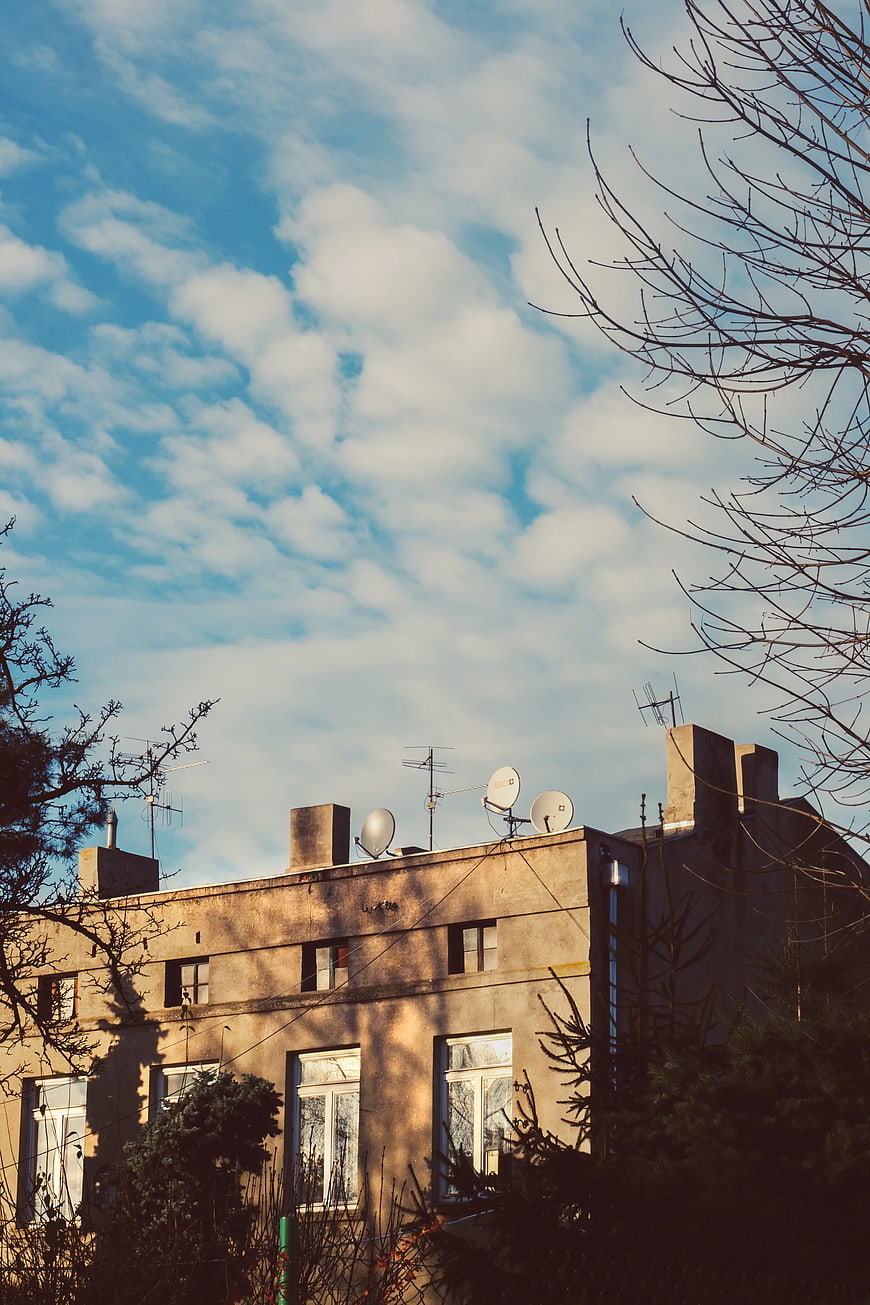Old Tenement Building with Satellite Dishes Against Blue Sky