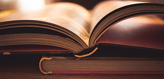 Close-up of open vintage book resting on stack of literature